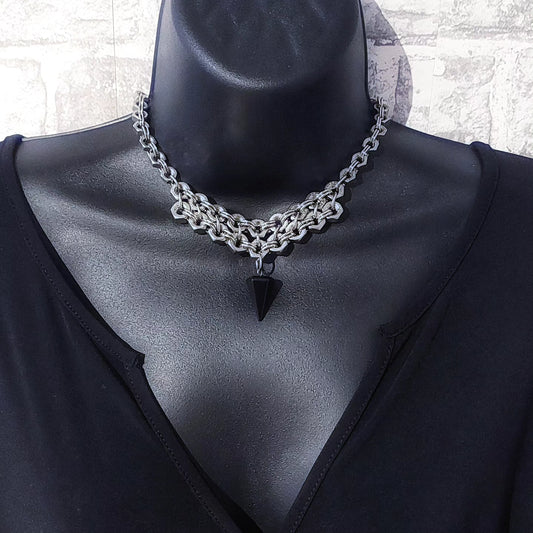 Silver chain necklace statement with black triangular pendant on mannequin wearing black top