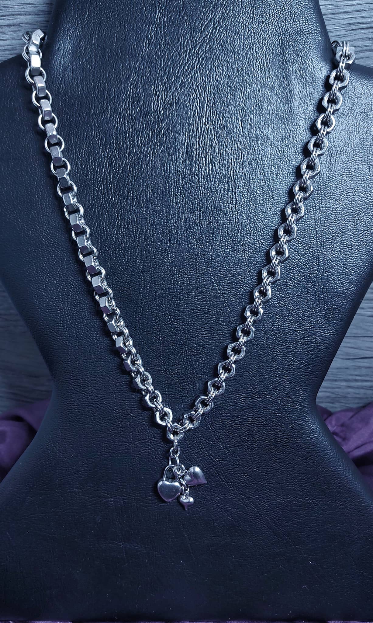 Silver chain necklace with small charms for charm necklace displayed on black stand