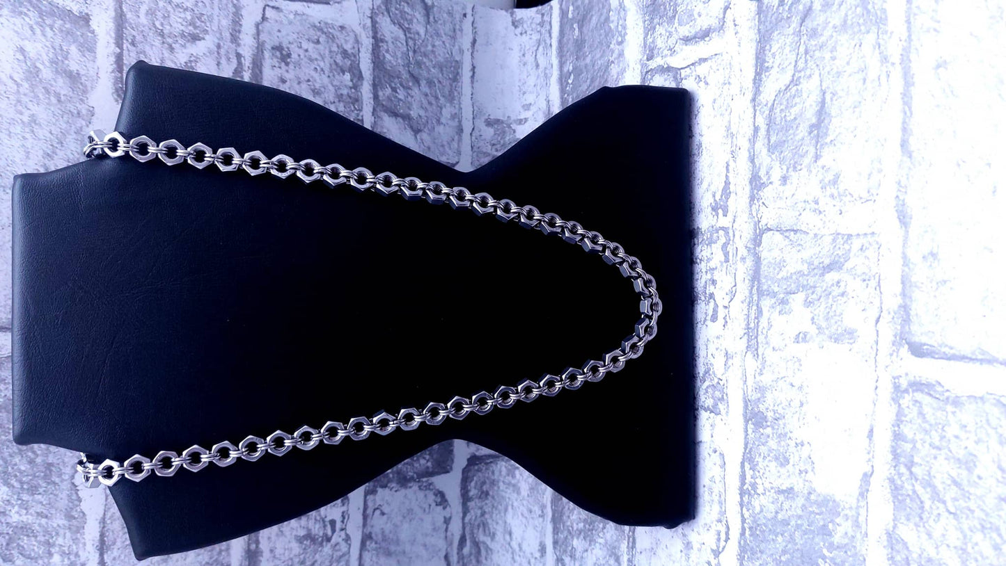 Silver chain necklace displayed on black necklace stand with brick wall background